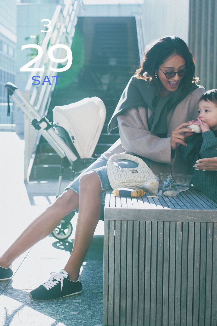 デニムハーフパンツにジャケットと肩掛けしたトップスとネイビーのスニーカーを合わせた着こなし