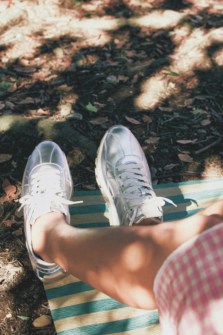 ピンクと白のギンガムチェックのスカートにシルバースニーカーを合わせた足元