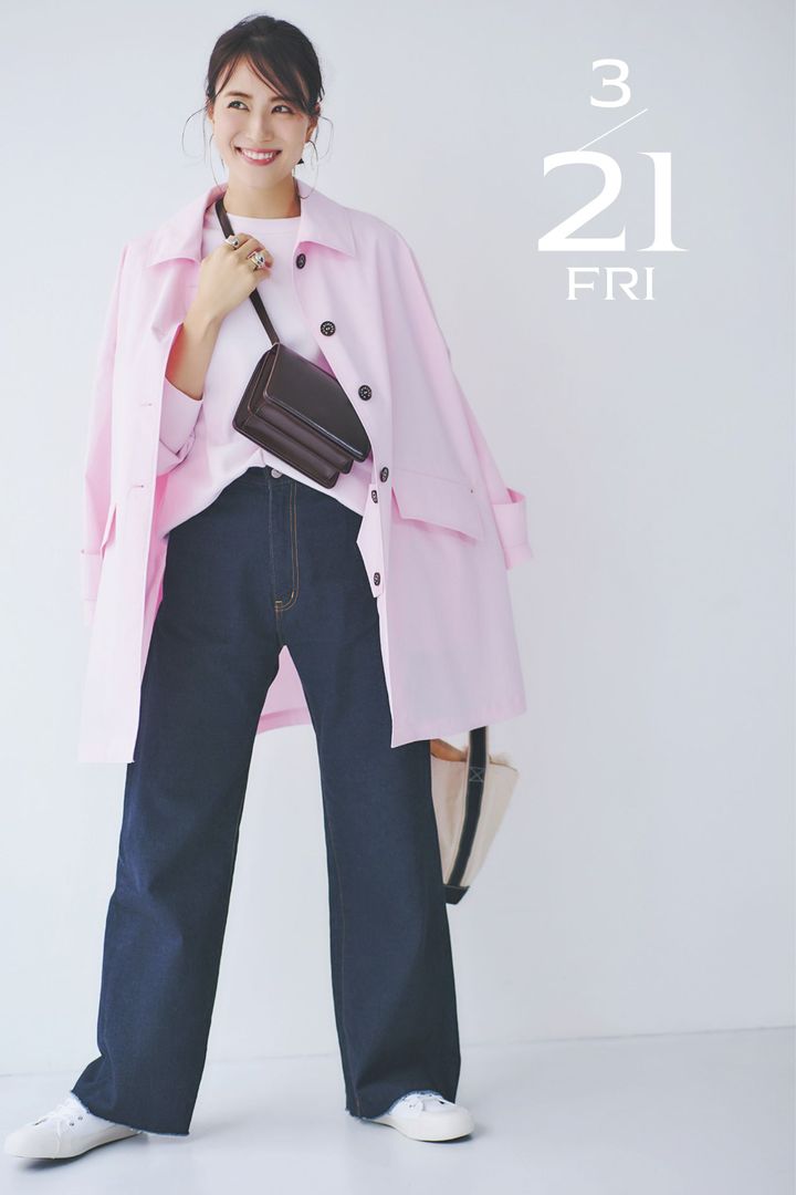 ピンクのスウェットとコートに濃紺の切りっぱなしデニムと白スニーカーとブラウンの斜めがけバッグを合わせた着こなし