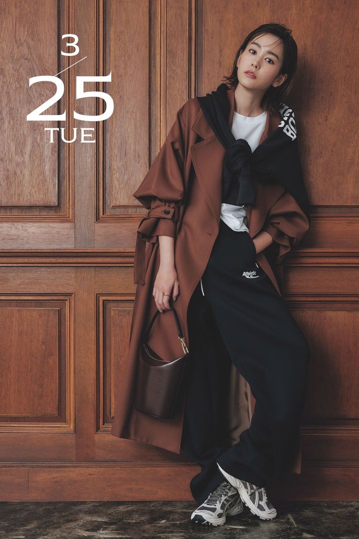 トラックパンツと白Tシャツにブラウンのトレンチコートを羽織ったコーデを着こなす桐谷美玲さん