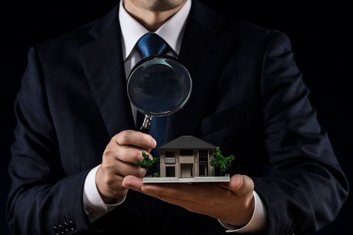 ハウスモデルとルーペを持つスーツの男