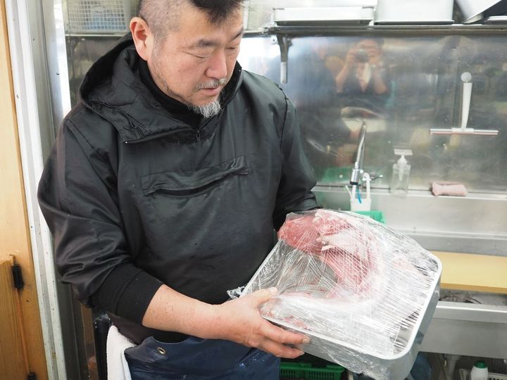 キハダマグロの巨大なカマ（エラの横にある胴体側の部位）を見せてくれる上田さん。「丁寧な仕事で魚のすべてを無駄なく活かす」がマルカマの基本方針の一つ
