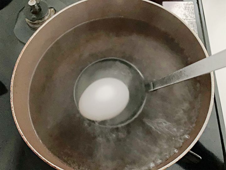お玉を使って卵を鍋の中に入れる