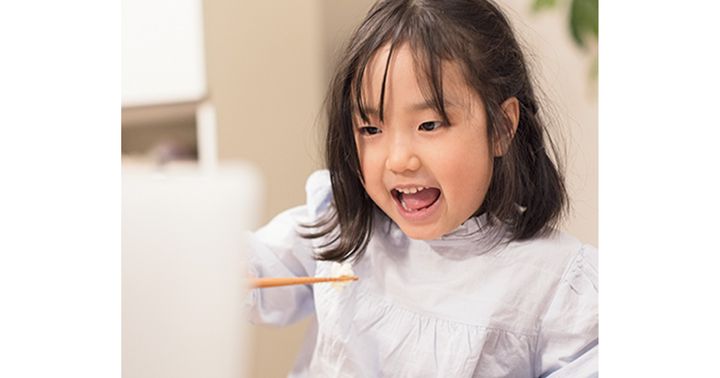 上手に子ども用のお箸を使って食べている様子