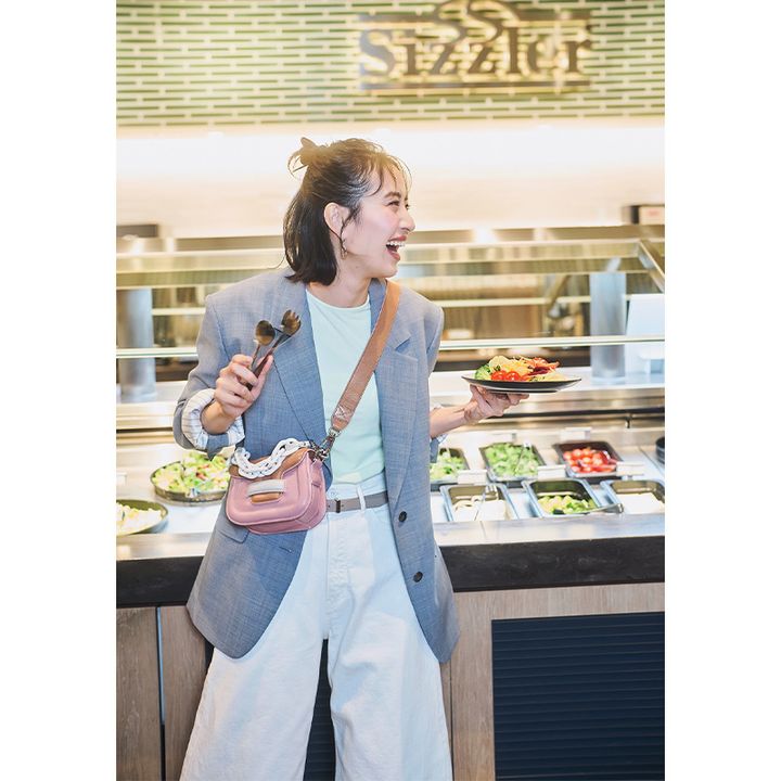 カラーTシャツと白デニムにグレーのジャケットを羽織ってサラダバーで野菜を取るママ