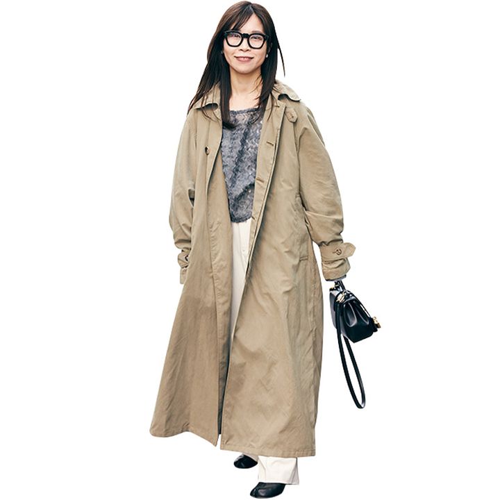 グレーのトップスと白パンツにベージュのアウターをざっくり羽織って黒縁メガネをかけた読者ママ