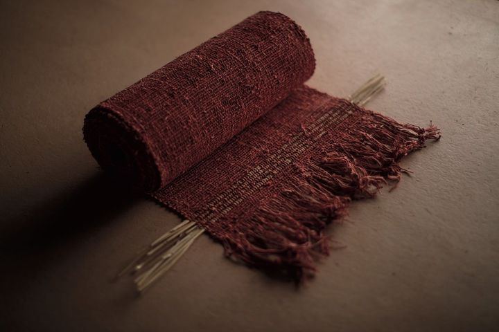 「土の部屋」に展示されたAAWAAの作品。赤土に埋めた丹後の絹布を和紙にして、藤糸を躯体に巻きつけ手織りした丹色の反物。Photo_ Kim Ilda