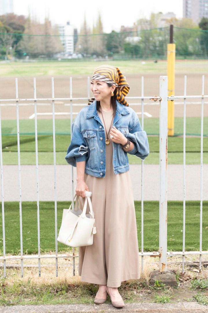 デニムジャケット... Maison Margiela、ジャンプスーツ... MADISONBLUE、シューズ ... Sergio Rossi、バッグ... HERMÉS、スカーフ... LANVIN、ピアス...Cream dot.、レザーネックレス...STUDIO CHERIE、バングル...STUDIO CHERIE