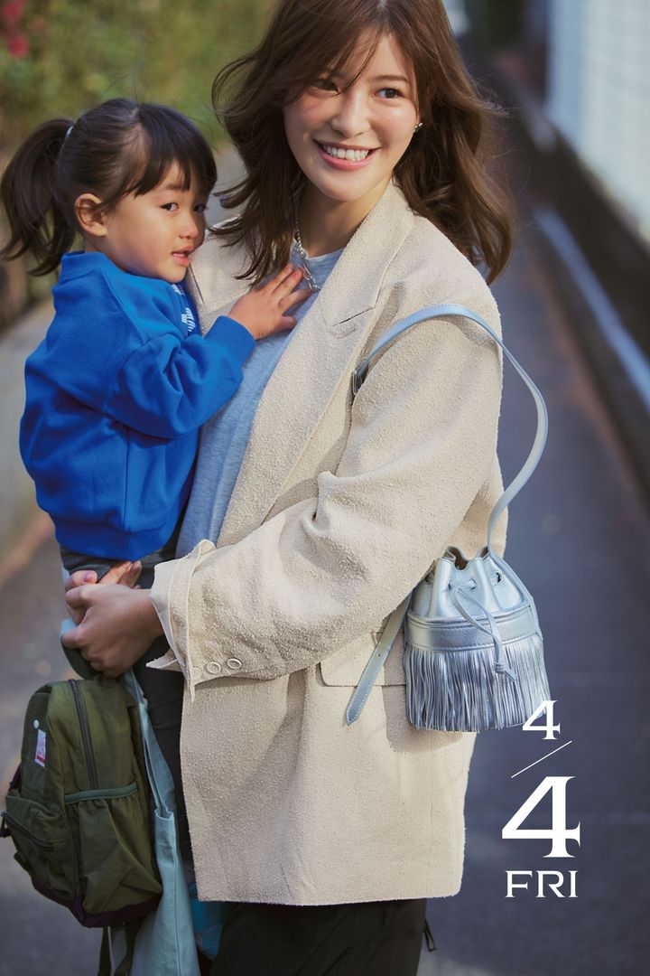 ゆったりシルエットのジャケットにシルバーのバッグを肩掛けして子どもを抱っこする咲和希さん
