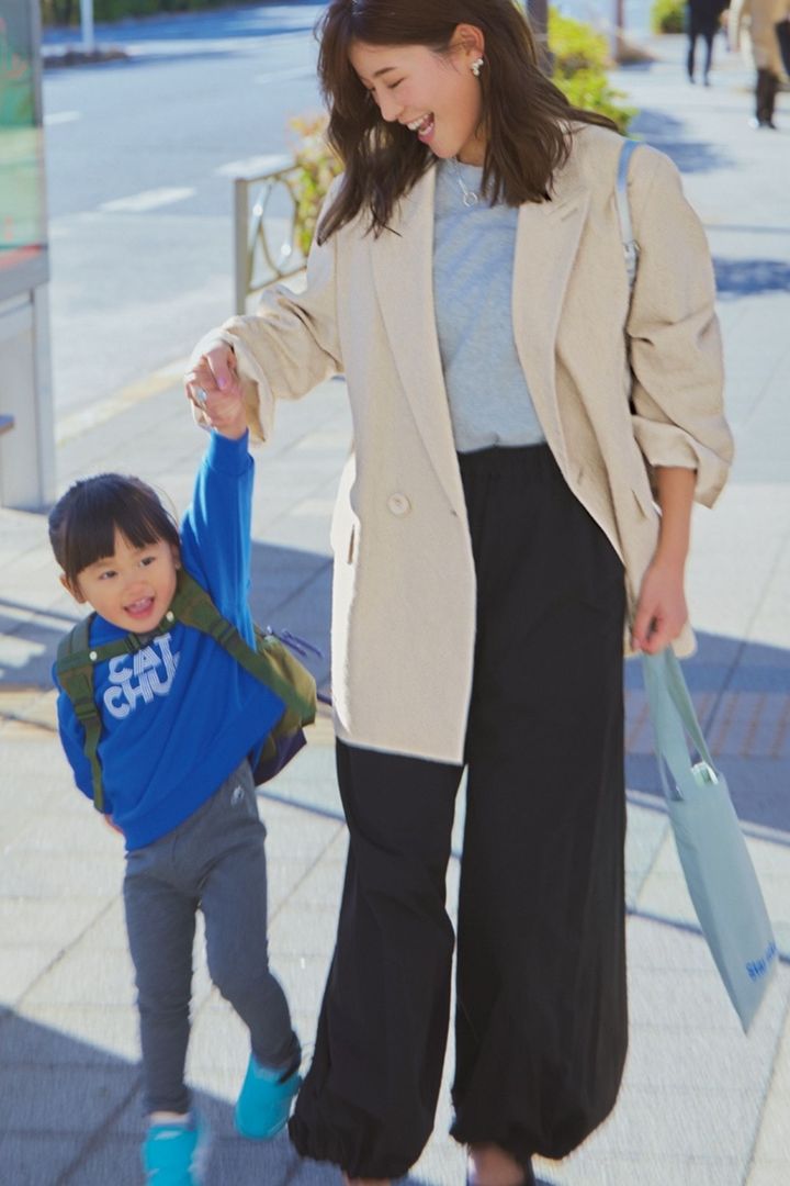 グレーのロンTとパラシュートパンツにオーバーサイズのジャケットを着て子どもと手を繋ぐ咲和希さん