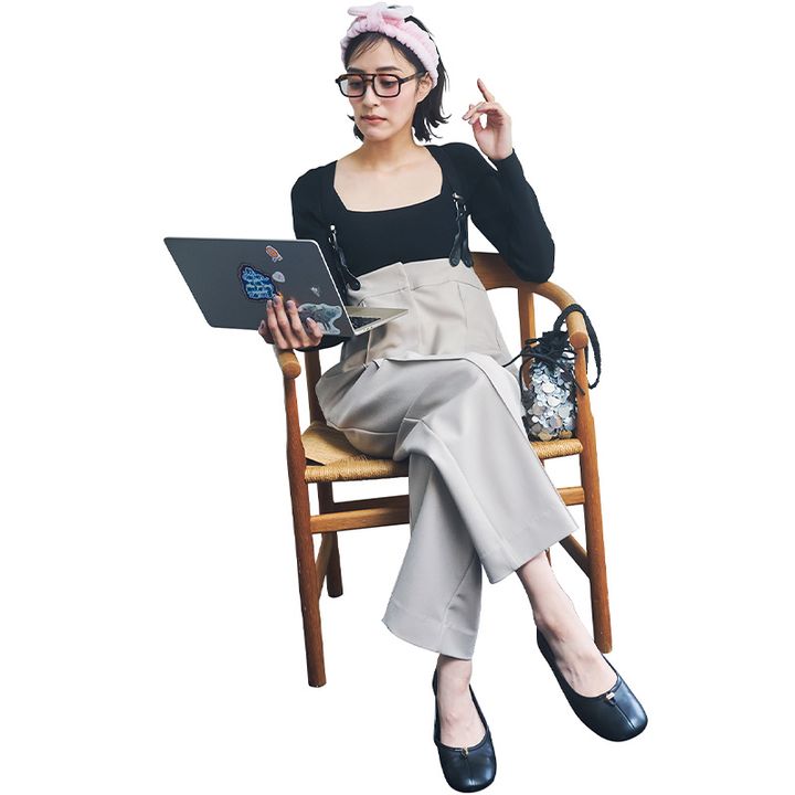 黒のスクエアネックカットソーにサスペンダー付きパンツを合わせてPCで仕事するママ