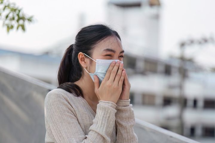口元を押さえて笑うマスクをつけた女性