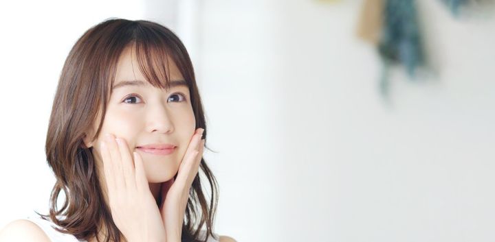 両頬を触って口角を上げる女性