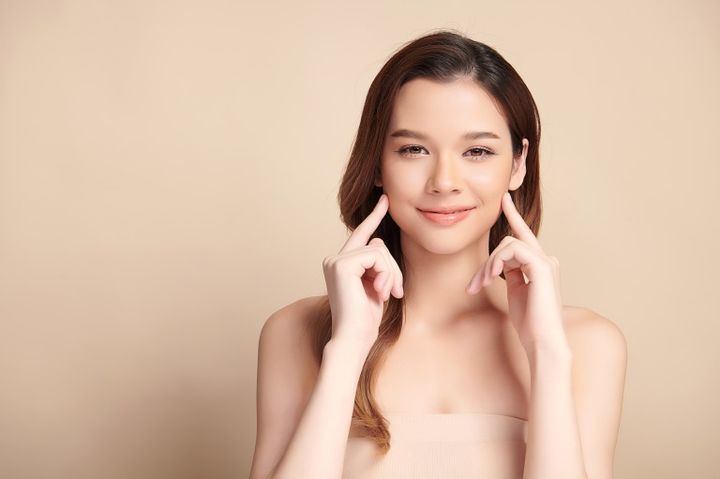 両頬に人差し指を置く女性 笑顔の練習イメージ