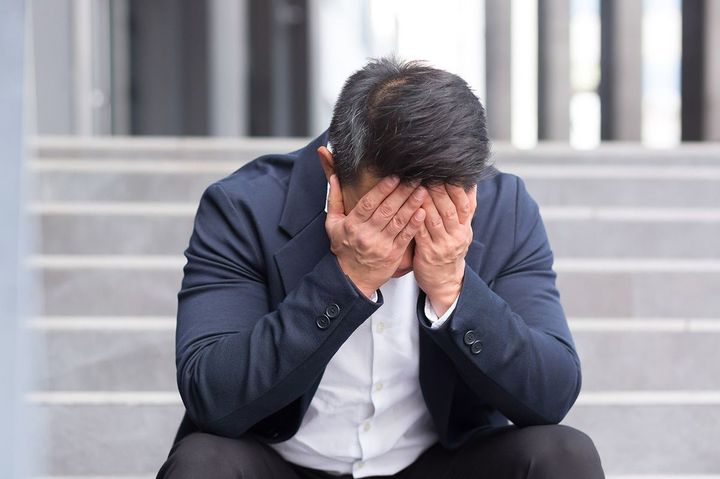 両手で顔を覆って座り込んでいる男性