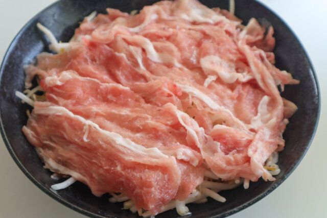 耐熱皿にもやしを広げ、その上に豚肉を並べるようにのせる。