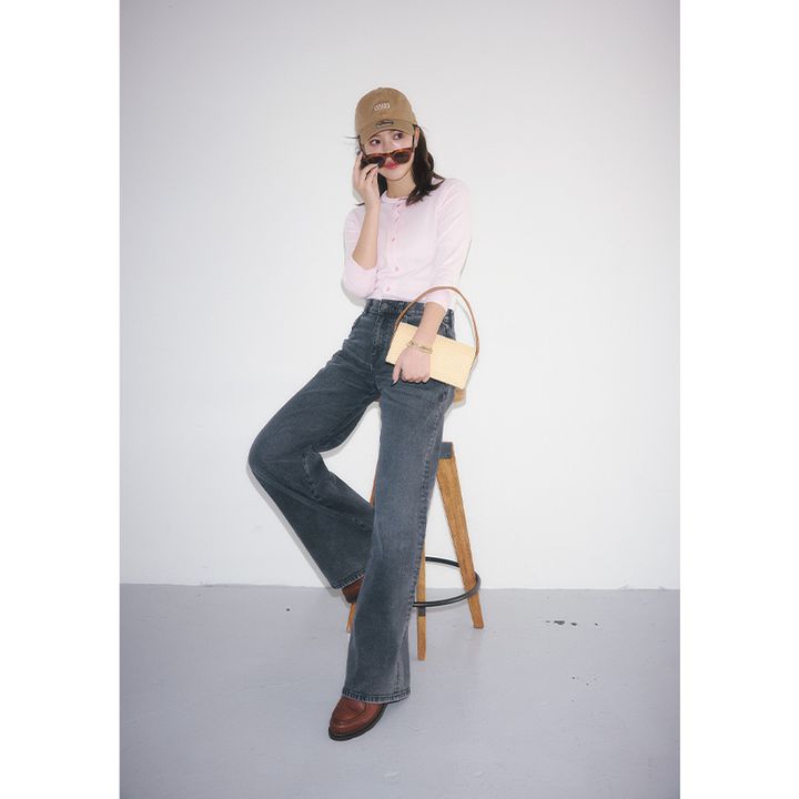 ディーゼルの緩やかなフレアのグレーデニムにピンクのカーディガンをインしてキャップやミニバッグを合わせたコーデ