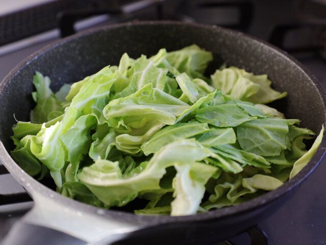 フライパンに、洗って水分が残ったままの春キャベツの葉をひと口大にちぎって入れる。