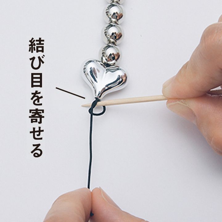 ハートのビーズの先端でマツバコードを玉結びする