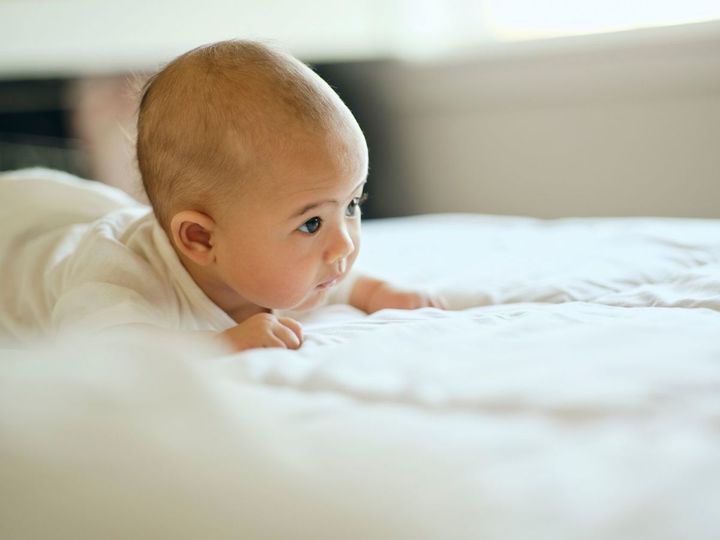 ベッドの上で前を見つめている赤ちゃん
