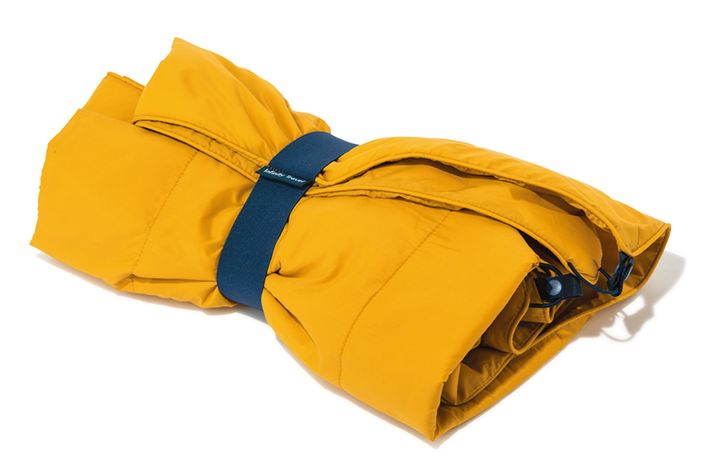 小さく畳めるゴムバンド付きのブランケットは、中綿入りで暖かく、ふんわりとした肌触りが気持ちいい。クッション代わりにもなり、アウトドアにはもちろん、フライトのお供にも。