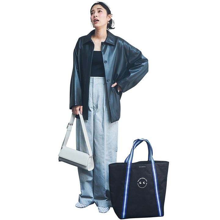 黒のカットソーとグレーのワイドデニムにエコレザージャケットを羽織って白バッグとシューズを合わせた着こなし