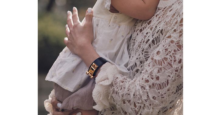 子どもを抱っこするママの手元についたエルメスのレザーブレスレット