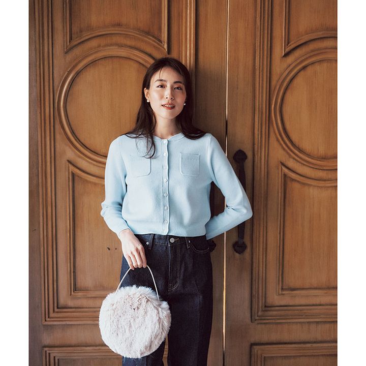 パウダーブルーのコンパクトなポケットつきカーデに濃い色のデニム、ファーバッグのコーデ