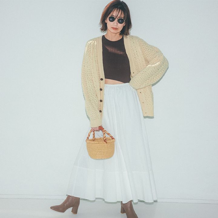 手編み感のあるざっくりカーデに、白のスカート、ブーツのコーデ
