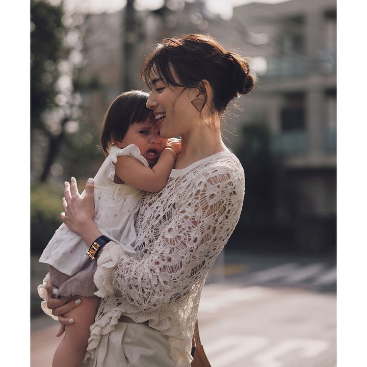エルメスのレザーピアスとブレスレットをつけた泣いている子どもを抱っこするママ