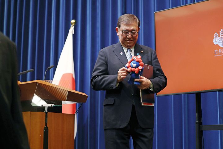 大阪・関西万博の公式キャラクター「ミャクミャク」を手に持つ石破首相（2025年4月1日、時事）