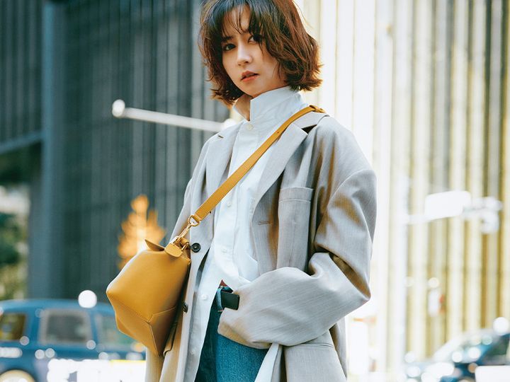衿を立てた白シャツにビッグサイズのジャケットを羽織ってロエベのバッグを斜めがけした河北麻友子さん