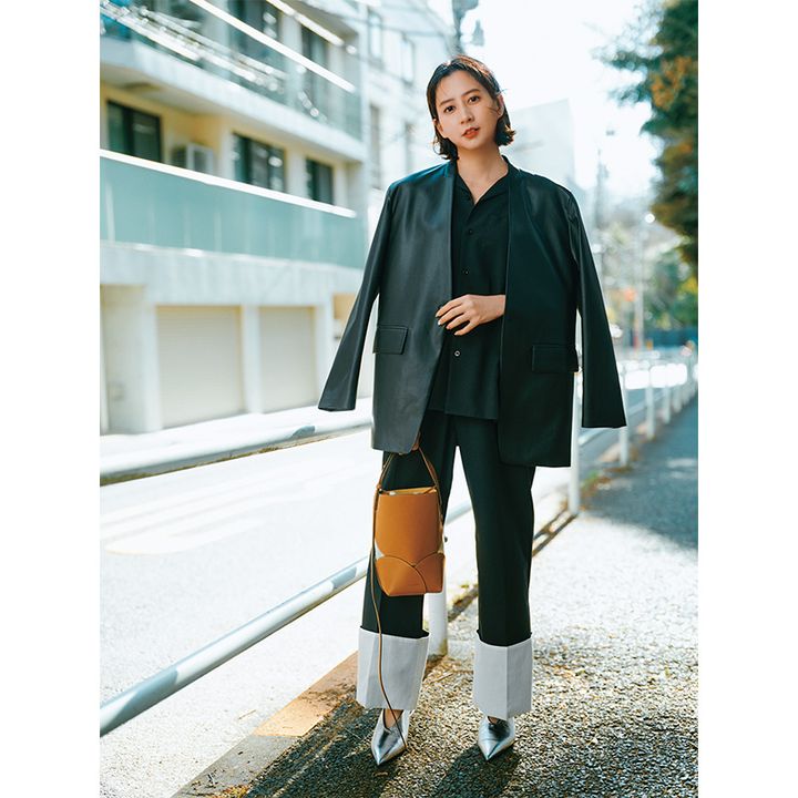 ブラックのシャツとジャケットい白のターンアップが特徴的なパンツとジルサンダーのシルバーのパンプスやブラウンのバッグを合わせたコーデ