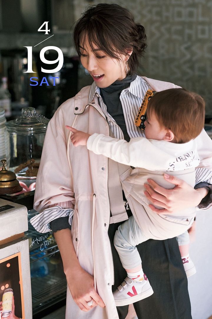 グレーのタートルロンTにストライプシャツとピンクのアウターを重ねて赤ちゃんを抱っこするママコーデ