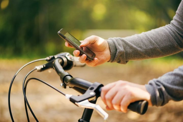 自転車に乗りながらスマホを使用している男性の手元