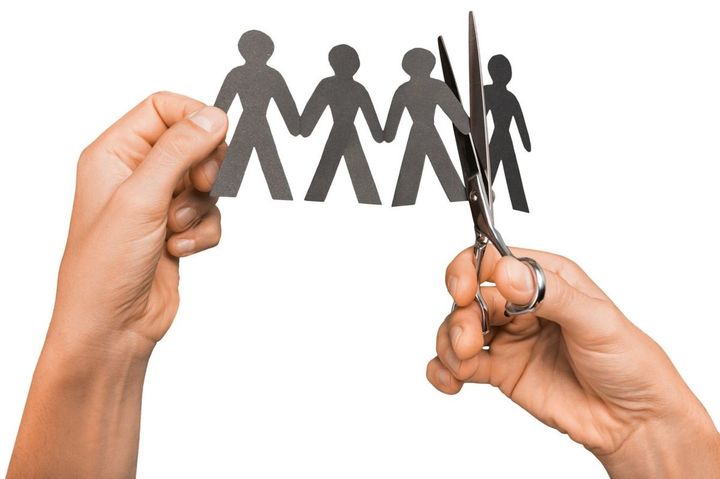 つながった紙製の人形をハサミで切る人