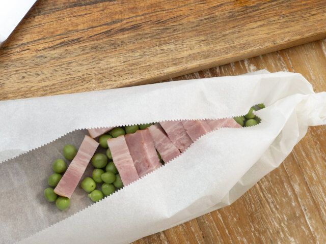 ①のグリーンピースと②のベーコンを、クッキングシートで包みます。