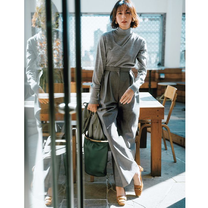 グレーのニットの重ね着にグレーのパンツを合わせたワントーンコーデにトッズのブラウンのバックスリングつきのシューズを履いた河北麻友子さん