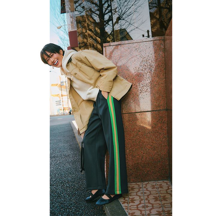 サイドにグリーンとベージュのラインが入ったスウェットパンツとパーカにジャケットを羽織った着こなし