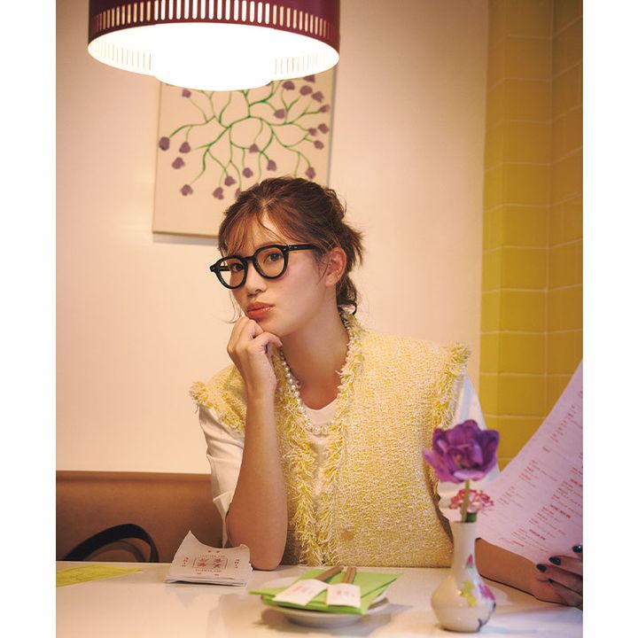 白Tに黄色ジレを羽織って黒縁メガネやパールネックレスを身につけた咲和希さん