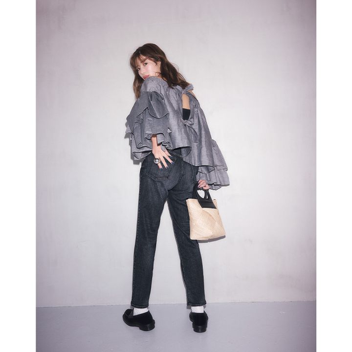 レッドカードの黒デニムパンツとツヤ感のあるフリルブラウスを合わせた咲和希さんの後ろ姿