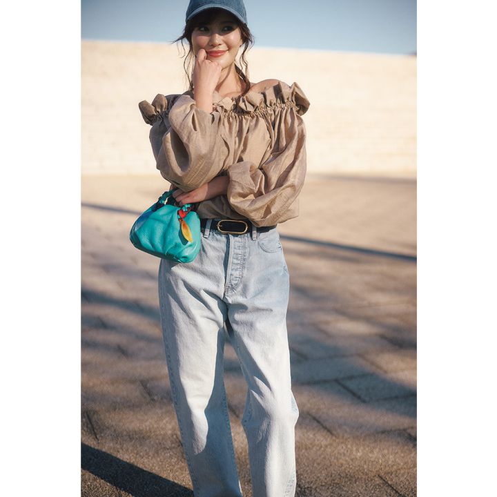 ブラウンのオフショルダーブラウスを淡いブルーのデニムやキャップでカジュアルに着崩したコーデ