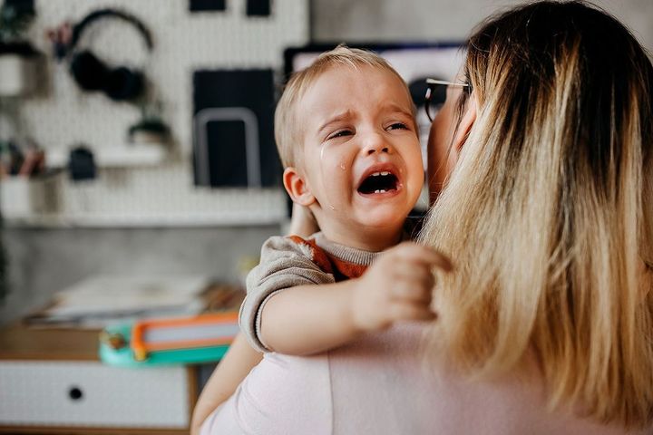 泣いている子供を抱く母親