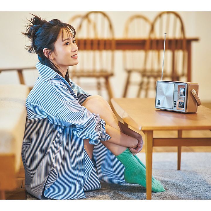 ストライプのシャツとショートパンツのセットアップを着てソファの前に座る前田敦子さん