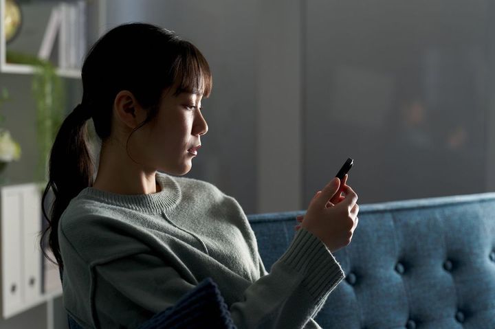 スマホを憂鬱な表情で見つめている女性