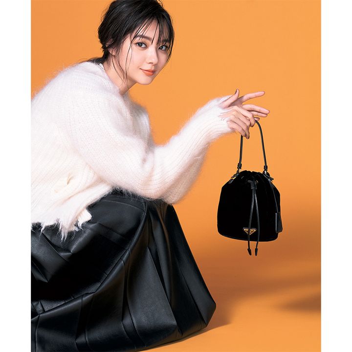 白のふわふわニットと黒スカートにプラダのベルベットのミニ巾着バッグを持った新川優愛さん
