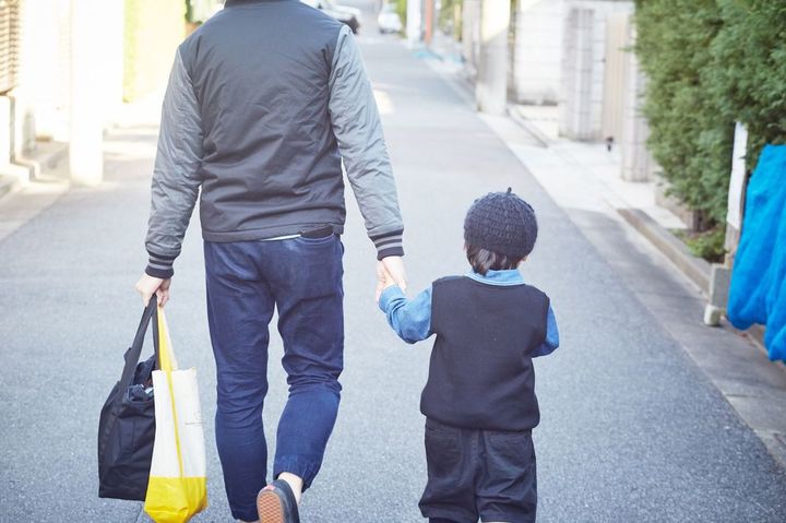 子供の手を引いて歩く父親