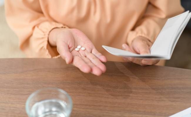 手帳を見ながら服薬する女性の手元のイメージ