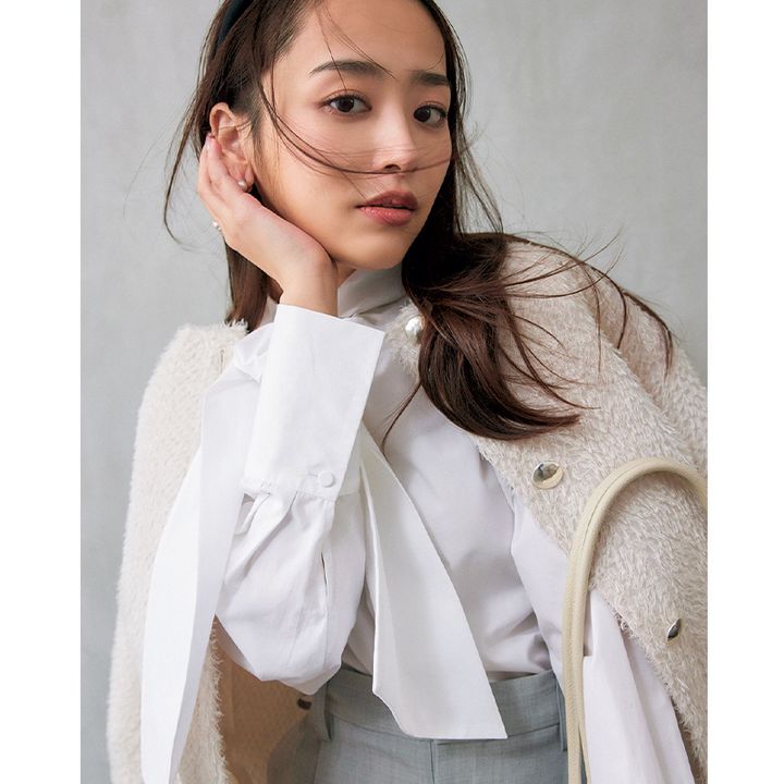 白のボウタイブラウスにジャケットを肩掛けした近藤千尋さん