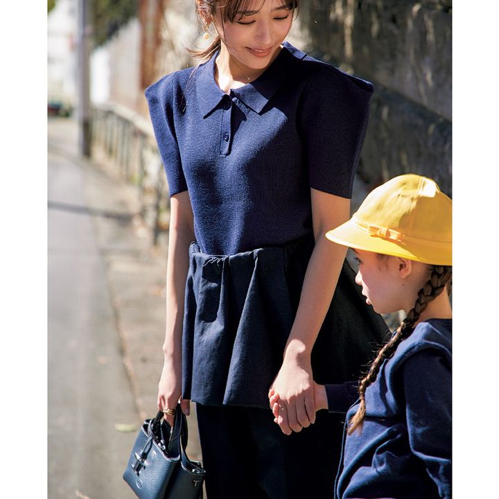 肩がデコラティブなデザインのネイビーのポロニットにスカートとパンツをレイヤードした登園スタイル